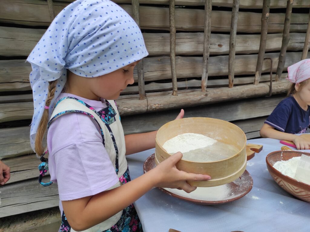 Дівчинка просіює борошно через сито