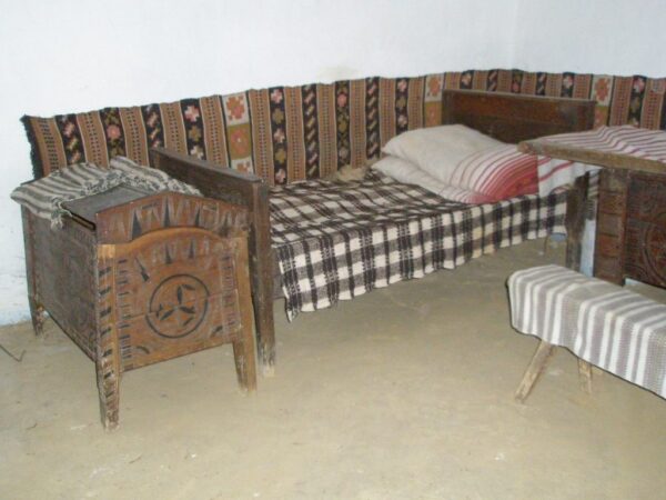 Фрагмент інтер'єру житла: дерев'яна скриня, ліжко з веретою, килим-залавник